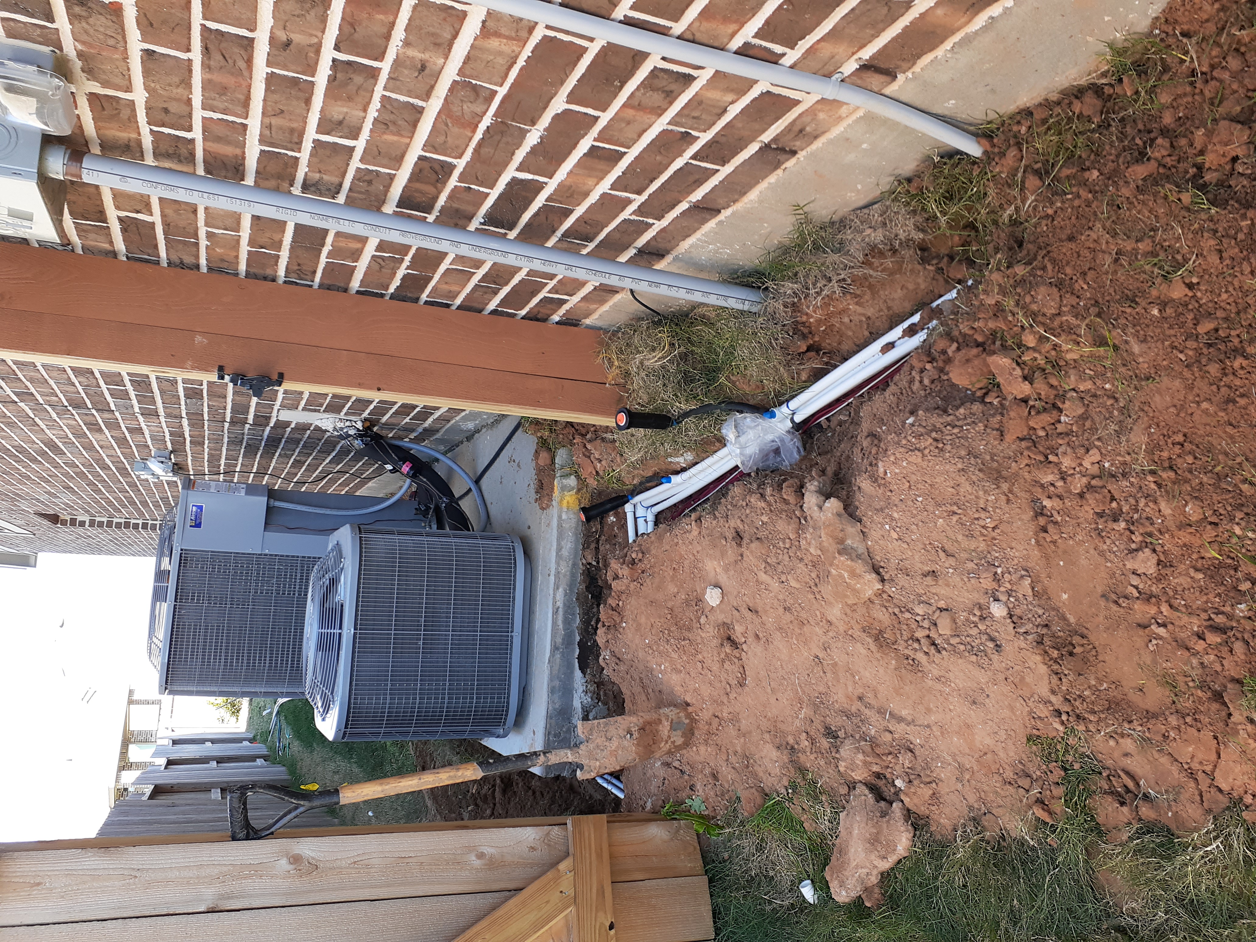 Sprinkler manifold and pop-up head installed beside the AC unit and brick patio at the Glencorse property