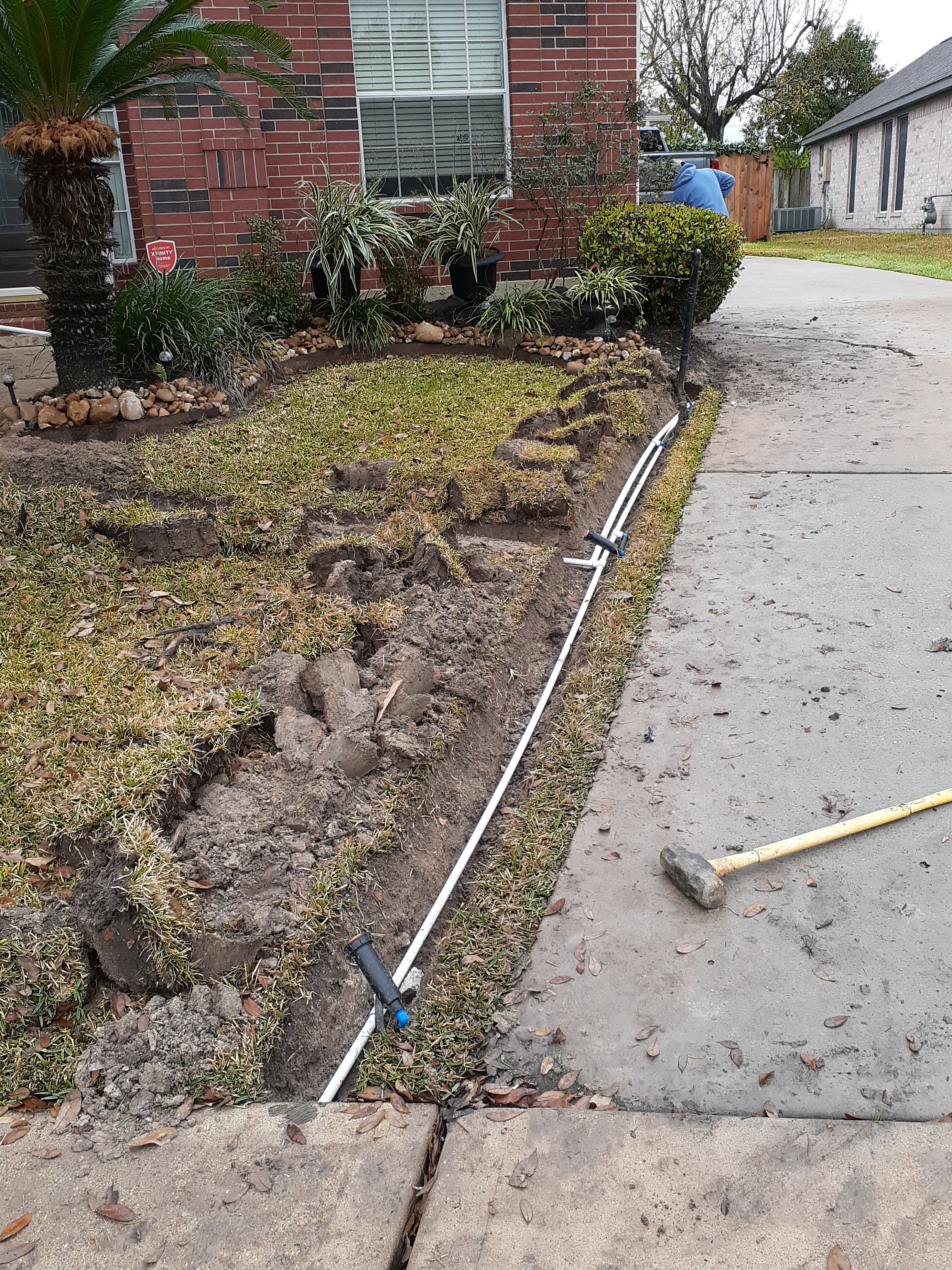 Front yard planter bed install with sledgehammer staged on the driveway and fresh PVC running through the bed