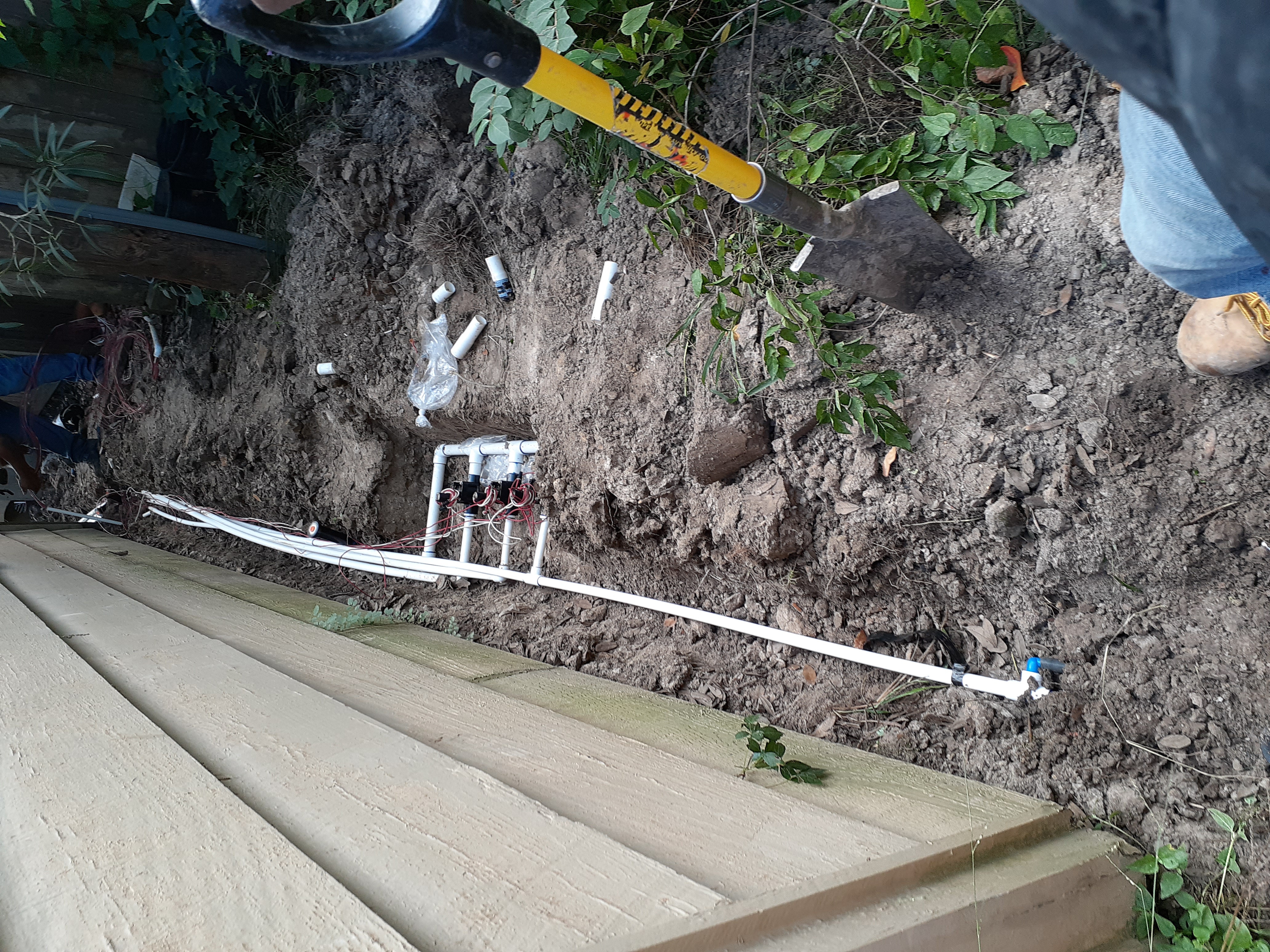 Close-up of a sprinkler zone valve manifold being wired in a freshly dug trench